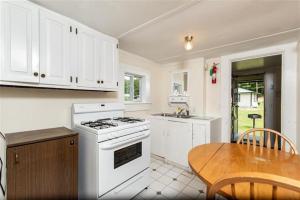cocina con estufa blanca y mesa de madera en Perry's Motel and Cottages, en North Conway