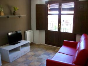 a living room with a red couch and a television at Apartamentos San Gregorio in Alquézar