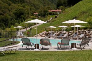 a group of chairs and umbrellas next to a pool at Piccola Valle in Vobarno