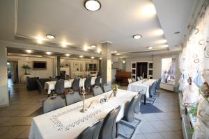 a dining room with white tables and chairs at Rezydencja Legrams in Darłowo