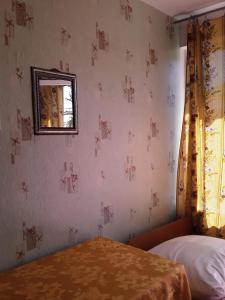 Schlafzimmer mit einem Bett und einem Wandspiegel in der Unterkunft Zeleniy Dvorik Guest House in Novy Afon