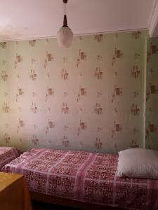 ein Schlafzimmer mit einem Bett und einer Tapetenwand in der Unterkunft Zeleniy Dvorik Guest House in Novy Afon