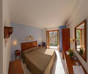 um quarto de hotel com uma cama e um espelho em Hotel Panoramic em San Vito lo Capo