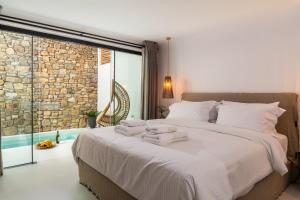a bedroom with a large bed with towels on it at Obsession Mykonos in Agios Stefanos