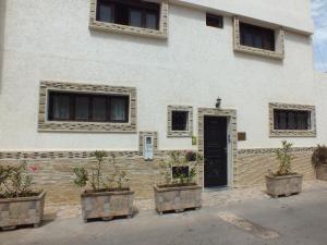 a white building with a black door and windows at Riad Les Chtis D'Agadir in Agadir
