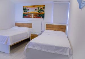 two beds in a room with white walls at Casana Hotel in Cúcuta