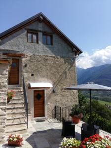 a stone house with a patio and an umbrella at Ossola dal Monte - Affittacamere in Crevoladossola