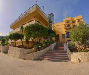 un edificio con escaleras y árboles delante de él en Hotel Panoramic, en San Vito lo Capo