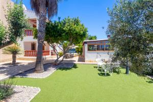 un jardín con césped y árboles frente a una casa en Villa Mali, en Ibiza