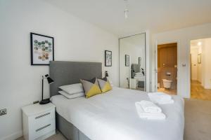 a bedroom with a large white bed with towels on it at Greenwich Two Bedroom Apartments in London