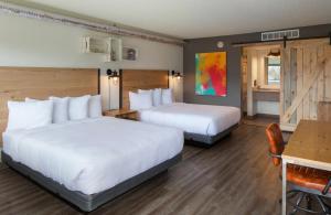 SCP Colorado Springs Hotel في كولورادو سبرينغز: غرفة فندقية بسريرين وطاولة