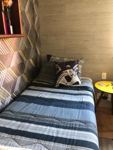 a bedroom with a bed with a blue blanket and a table at Bilingual Home in Belo Horizonte