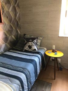 a bedroom with a bed and a yellow table at Bilingual Home in Belo Horizonte