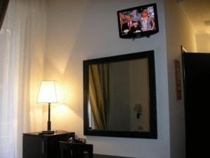 a mirror on a wall with a tv and a lamp at Roman Residence in Rome