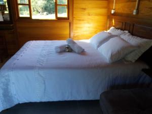 a large white bed with a teddy bear on it at Caminhos da Serra do Tabuleiro - Chalé Araucária in São Bonifácio