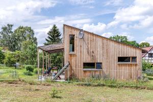 une maison en bois dans un champ avec une clôture dans l'établissement Studio Zempow, ökologisches Ferienhaus, à Zempow