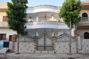 卢克索White Villa的一座白色的房子,有黑色的大门和两棵树