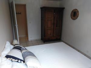 a bedroom with a bed and a wooden cabinet at Appart Terrasse Végétale bord Plages bassin in Arès