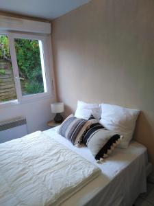 een slaapkamer met een bed met witte lakens en een raam bij Appart Terrasse Végétale bord Plages bassin in Arès