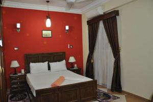 1 dormitorio con cama y pared roja en White Villa, en Luxor