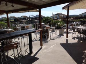 an outdoor patio with tables and chairs and umbrellas at Appart Terrasse Végétale bord Plages bassin in Arès