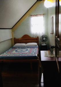a bedroom with a bed and a table and a window at Mayoyao View Inn in Banaue