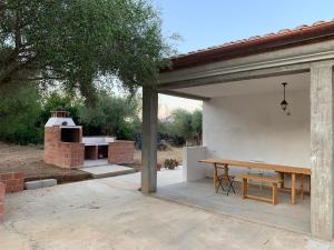 un patio con una mesa de madera y un horno de pizza en Sa Domu e Muru en Galtellì