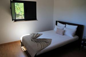 Una cama con sábanas blancas y una ventana en una habitación en Quinta JR - Casa de campo en Carregal