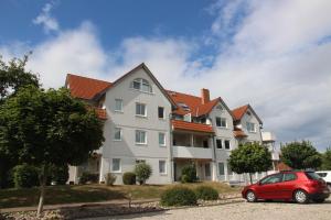 una casa con un coche rojo estacionado frente a ella en Ferienwohnung Schönfeld auf Fehmarn en Petersdorf auf Fehmarn