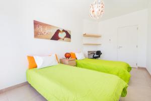 a bedroom with two beds with green sheets at Apartamento Praia Fuzeta in Fuzeta
