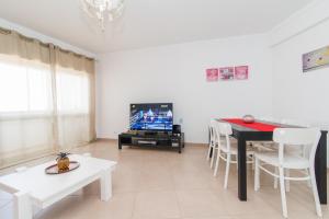 uma sala de estar com uma mesa e uma televisão em Apartamento Praia Fuzeta na Fuzeta