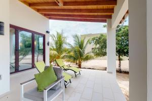 un patio con sillas verdes y vistas a la playa en Green Tower House en Placencia Village