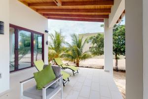 un patio con sillas verdes y vistas a la playa en Green Tower House, en Placencia Village