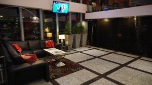 a lobby with a couch and a tv in a building at Hotel Las Cascadas in San Pedro Sula