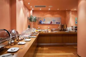 a restaurant with a long counter with food at Athens Center Square Hotel in Athens