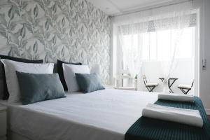 a bedroom with a bed with white sheets and blue pillows at 4U Lisbon Suites & Guesthouse VII Airport in Lisbon