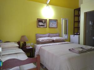 duas camas num quarto com paredes verdes em Pousada Enseada das Conchas na Ilha do Mel