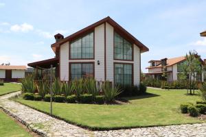 a house with glass windows on a lawn at Cabañas Molino del Rey in Tapalpa