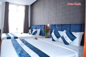 two beds in a hotel room with blue and white pillows at Mountain Town Hotel in Da Lat