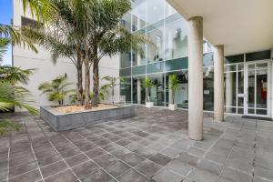 a courtyard in front of a building with palm trees at Seaside Apartment Getaway in Dromana