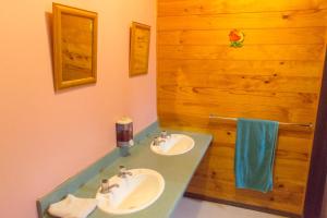 a bathroom with two sinks and a wooden wall at JunoHall Backpackers in Waitomo Caves