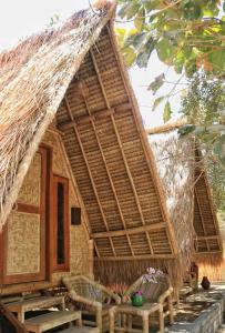 una cabaña de paja con una mesa delante en Gili Kampoeng en Gili Trawangan