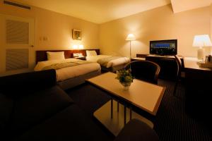 a hotel room with two beds and a couch at Hotel Aomori in Aomori