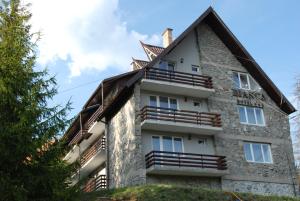 uma grande casa de pedra com um telhado de gambrel em Hotel Bianca em Beliş