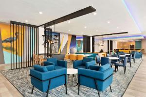 La Quinta by Wyndham Richmond-Sugarland في Richmond: غرفة انتظار مع كراسي وطاولات زرقاء