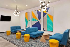 una sala de espera con sillas azules y una pintura en La Quinta by Wyndham Richmond-Sugarland, en Richmond