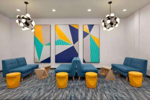 a waiting room with blue chairs and colorful paintings at La Quinta by Wyndham Richmond-Sugarland in Richmond