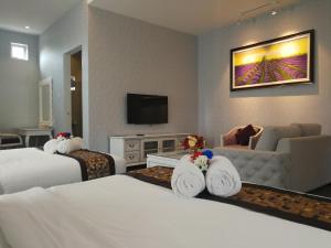 a hotel room with two beds and a television at Casa Bianca in Kluang