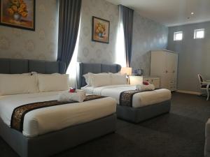 um quarto de hotel com duas camas e um sofá em Casa Bianca em Keluang