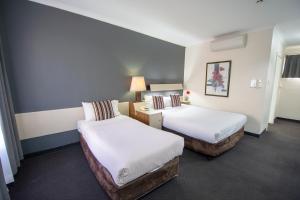 ein Hotelzimmer mit 2 Betten mit weißer Bettwäsche in der Unterkunft The Midcity Motor Lodge in Orange